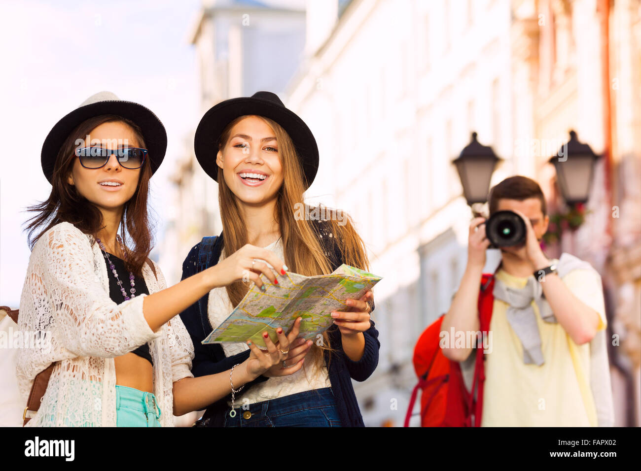 Girls together hold city map and guy shooting Stock Photo - Alamy
