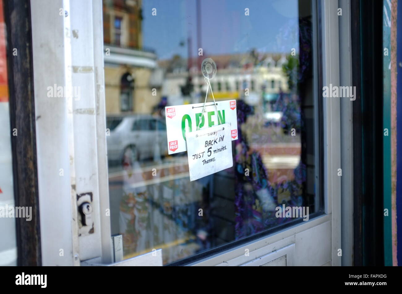 'Back in 5 Minutes' sign on top of 'Open' sign on glass café door. Stock Photo