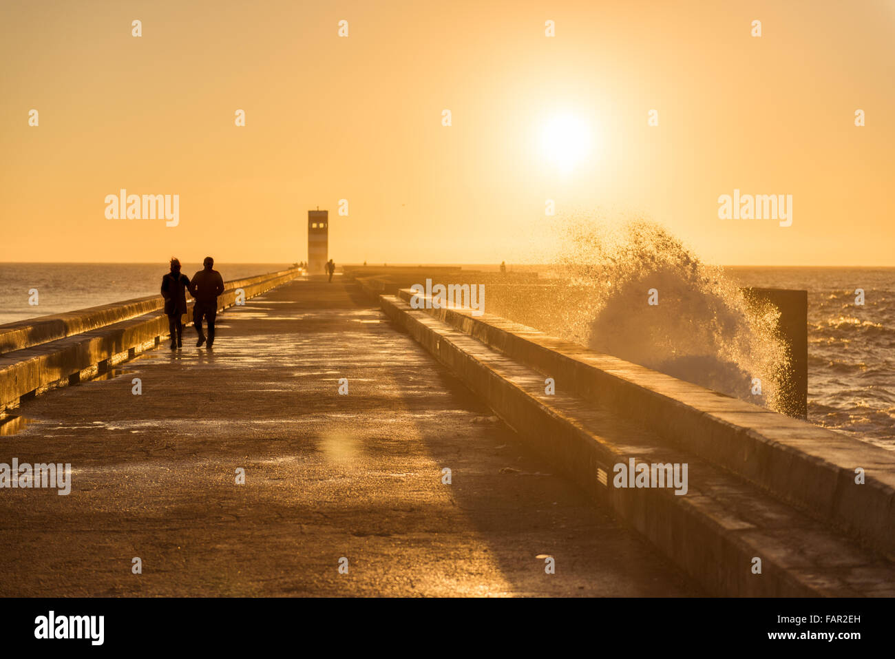 Couple walking on a dock with sunset light Stock Photo - Alamy