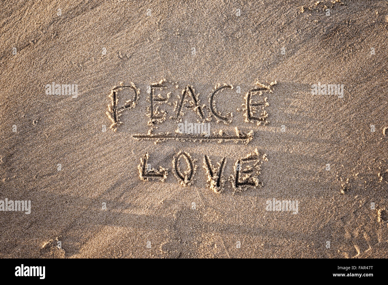 The words peace and love written in sand. Stock Photo