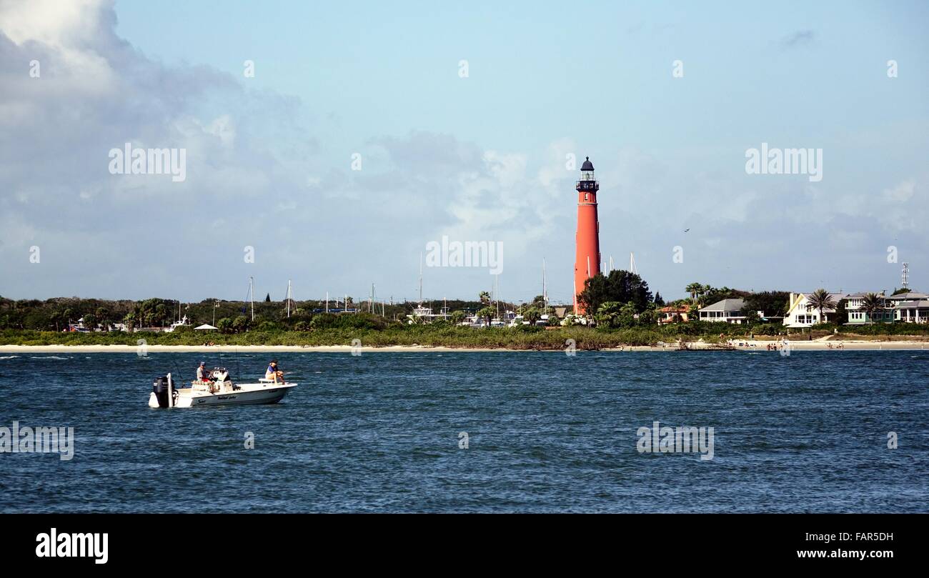 A fishing boat crosses in front of the Ponce de Leon inlet lighthouse. Stock Photo