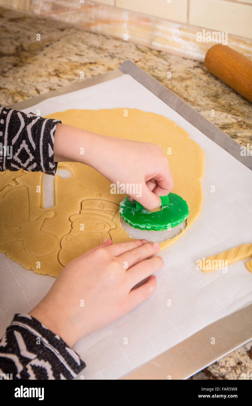 Ten year old girl using cookie cutters to cut out Christmas sugar