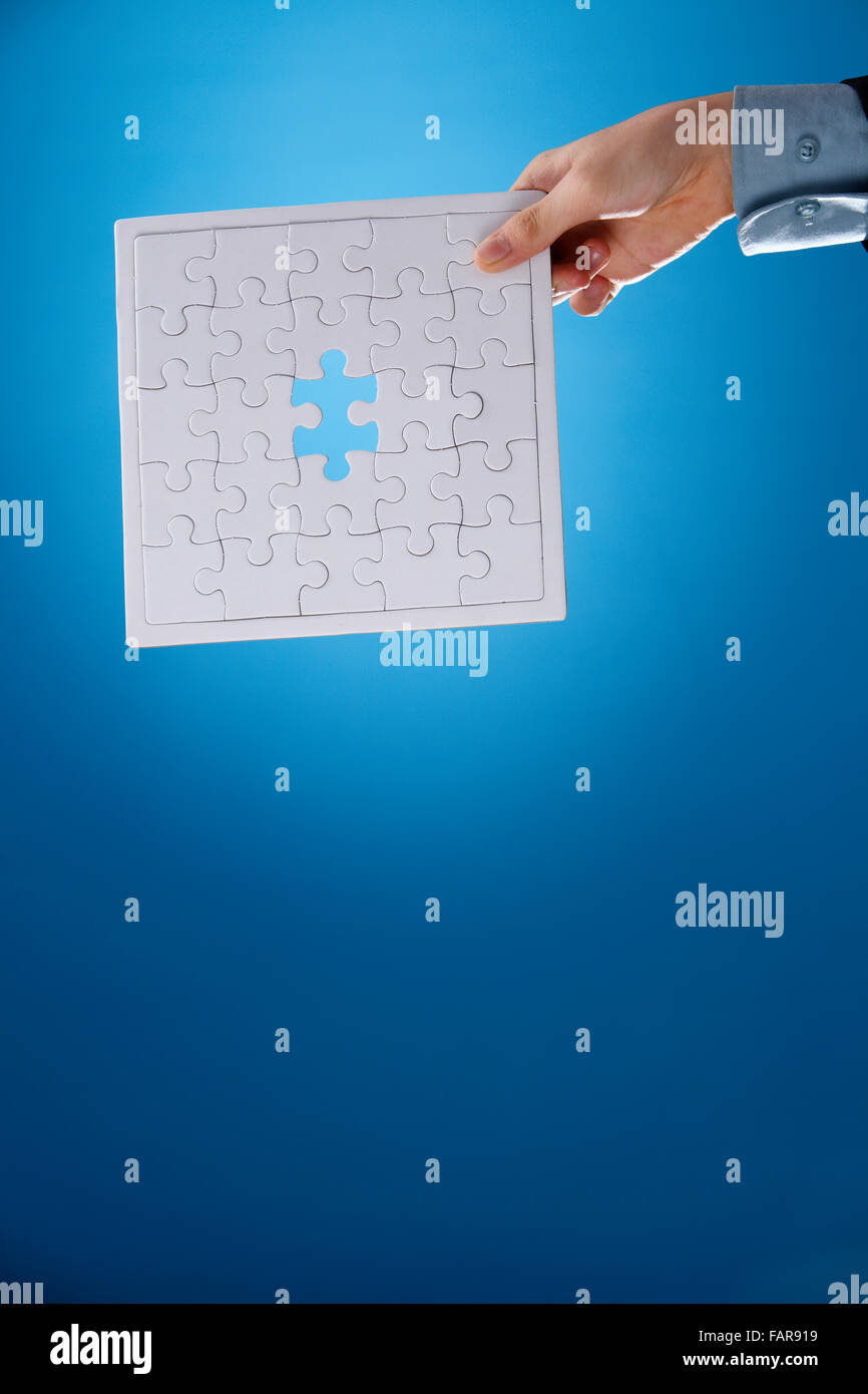 Human hand holding an incomplete jigsaw puzzle. Stock Photo