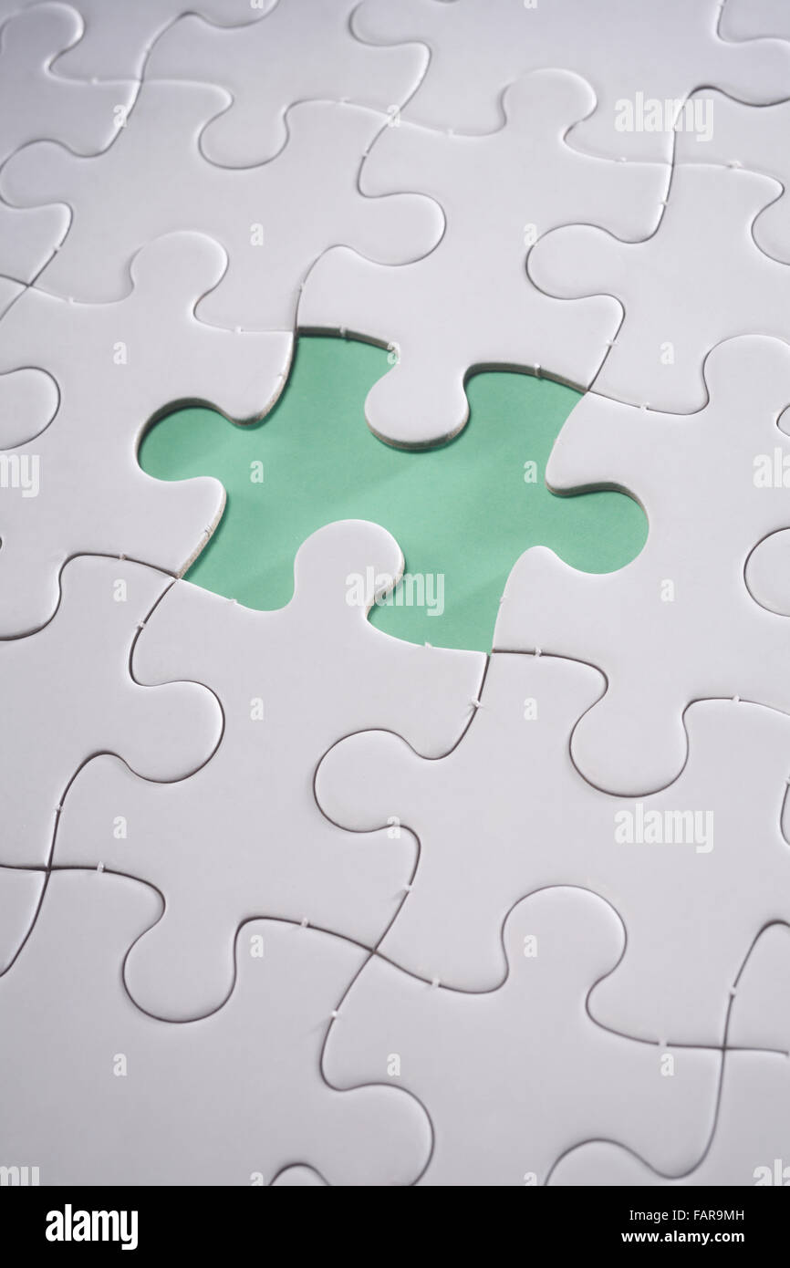 Jigsaw puzzle with missing piece isolated on green background. Stock Photo
