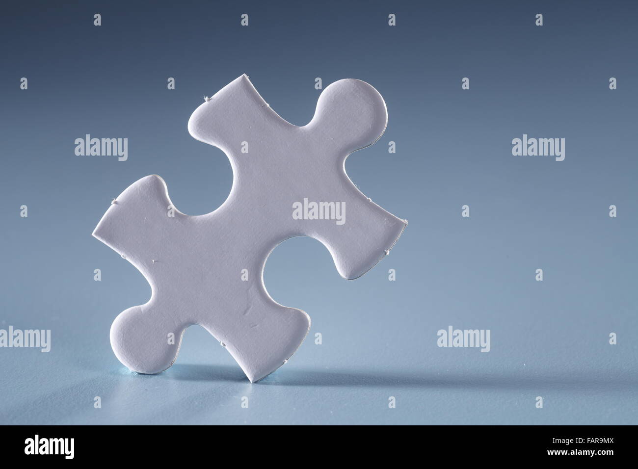 Single jigsaw piece isolated on the blue background. Stock Photo