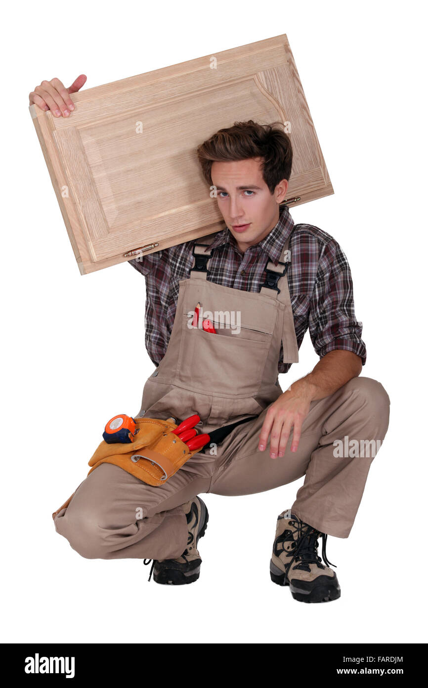 portrait of young cabinetmaker carrying cupboard door over shoulder Stock Photo