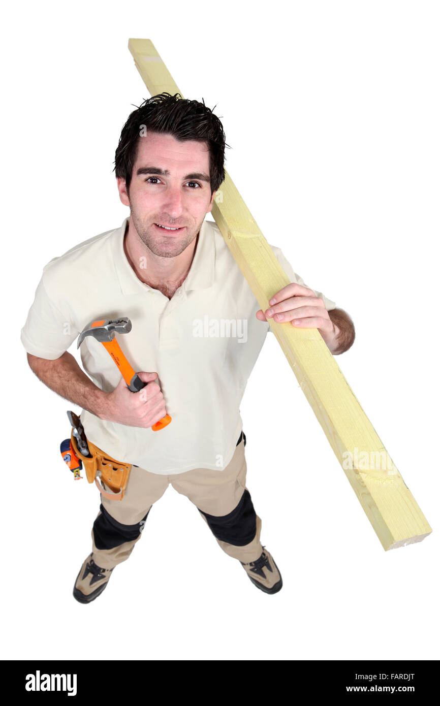 Handyman holding a hammer and carrying a wooden plank Stock Photo
