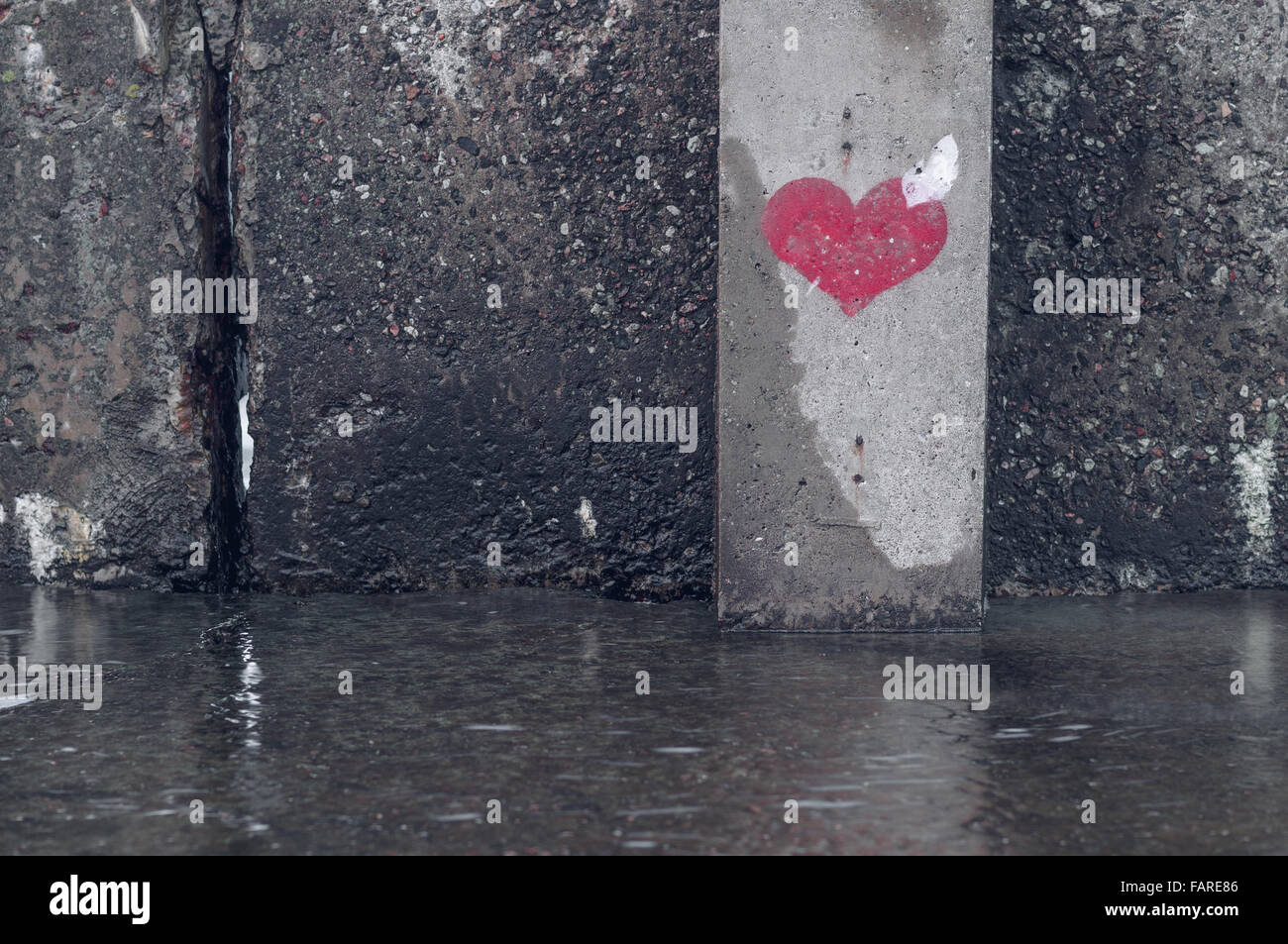 Red heart symbol painted on a wet grunge wall Stock Photo