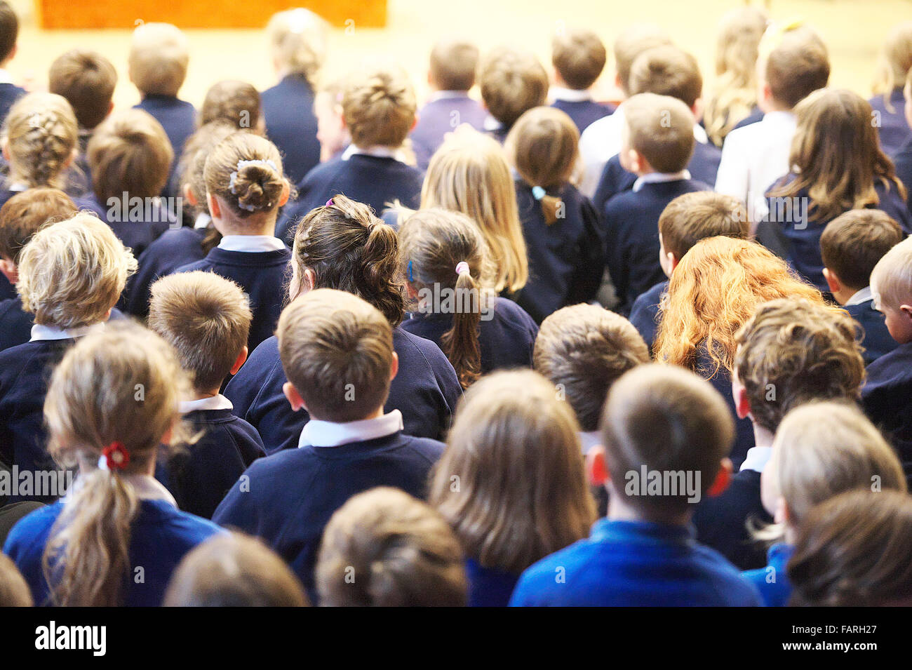 group of children sitting down in a school hall during a educational assembly at a small UK school Stock Photo