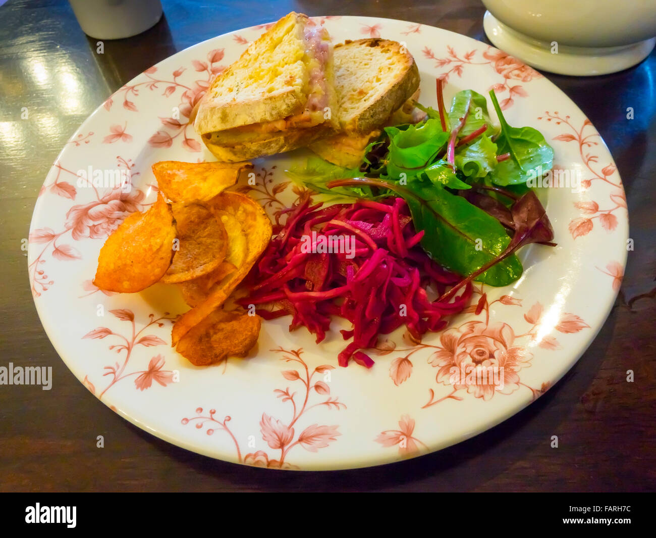 Toasted Ham and Cheese Sandwich with salad red cabbage and crisps on a  pink plate Stock Photo