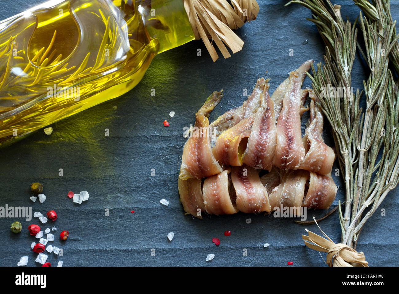 Anchovies with salt, oil and spices on black marble closeup Stock Photo