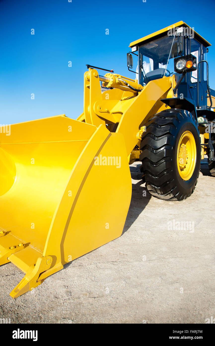 Bright yellow excavator on the background of blue sky Stock Photo