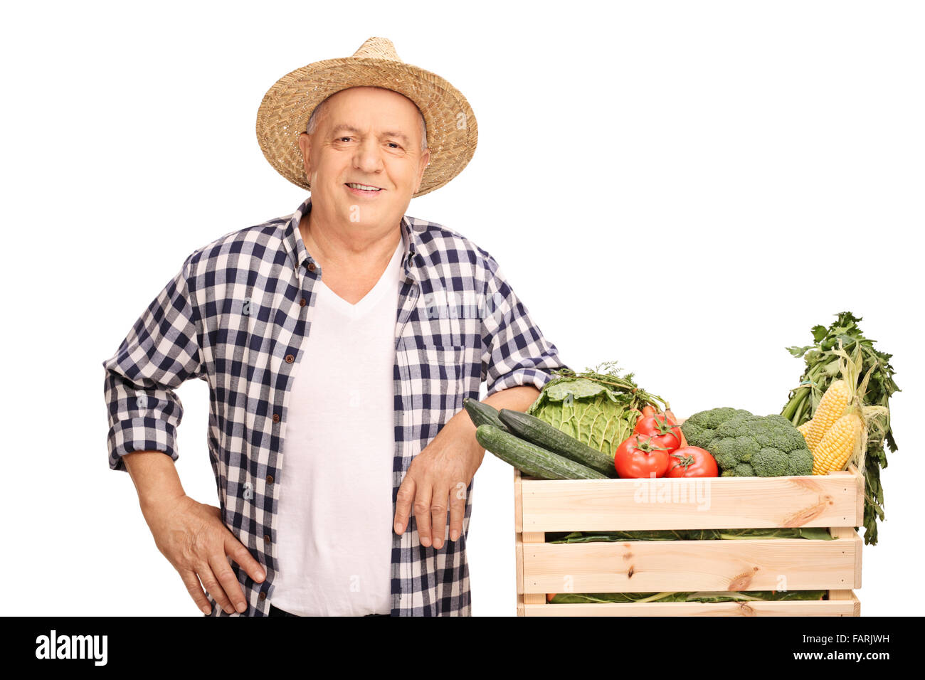 Mature farmer posing next to a wooden crate full of fresh vegetables ...