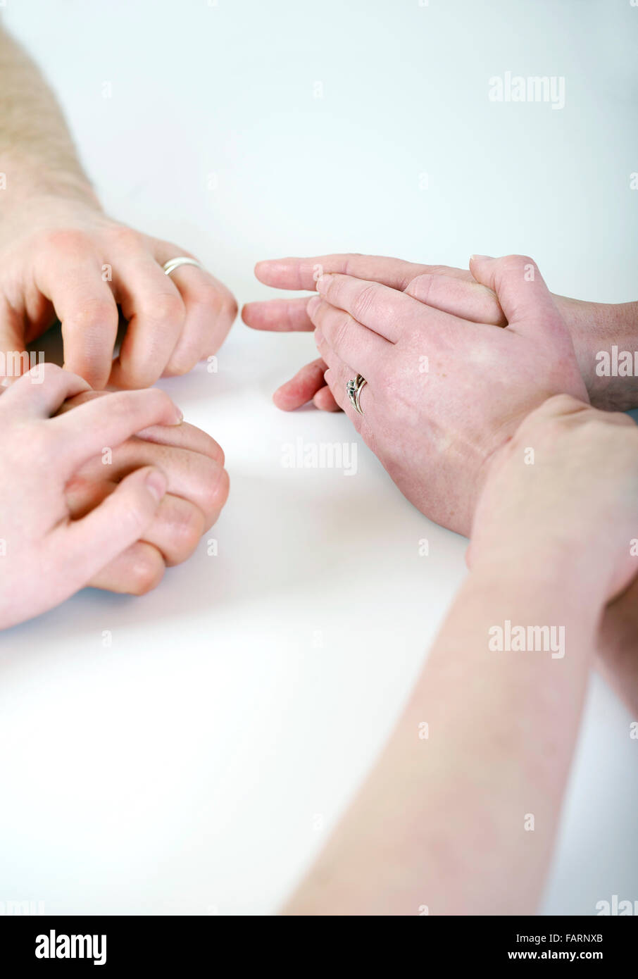 Child holds the hands of mother and father during a fragmented and strained relationship Stock Photo