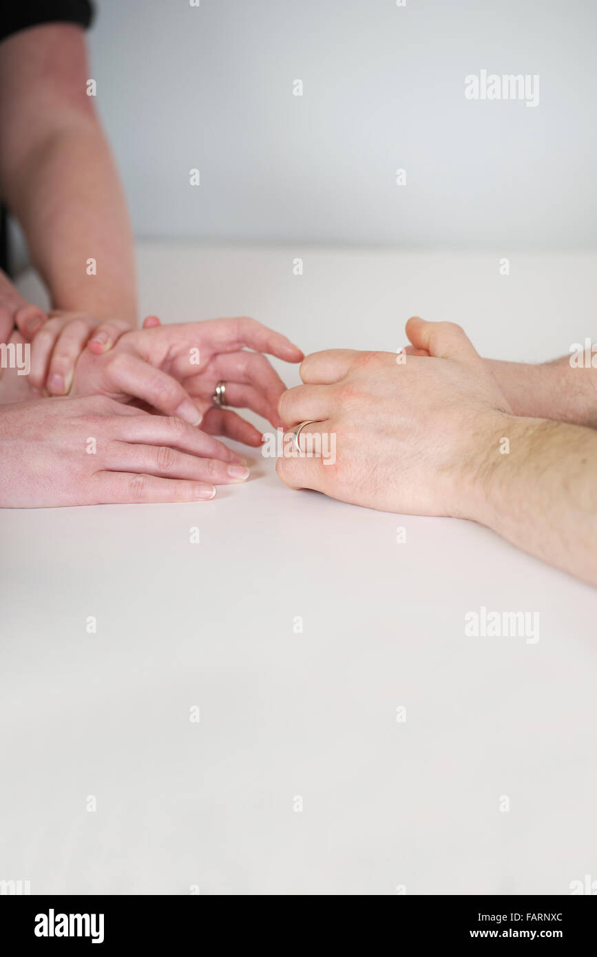 Young child grips the hands of mother and father, as the wife reaches out to the husband during a strained relationship Stock Photo