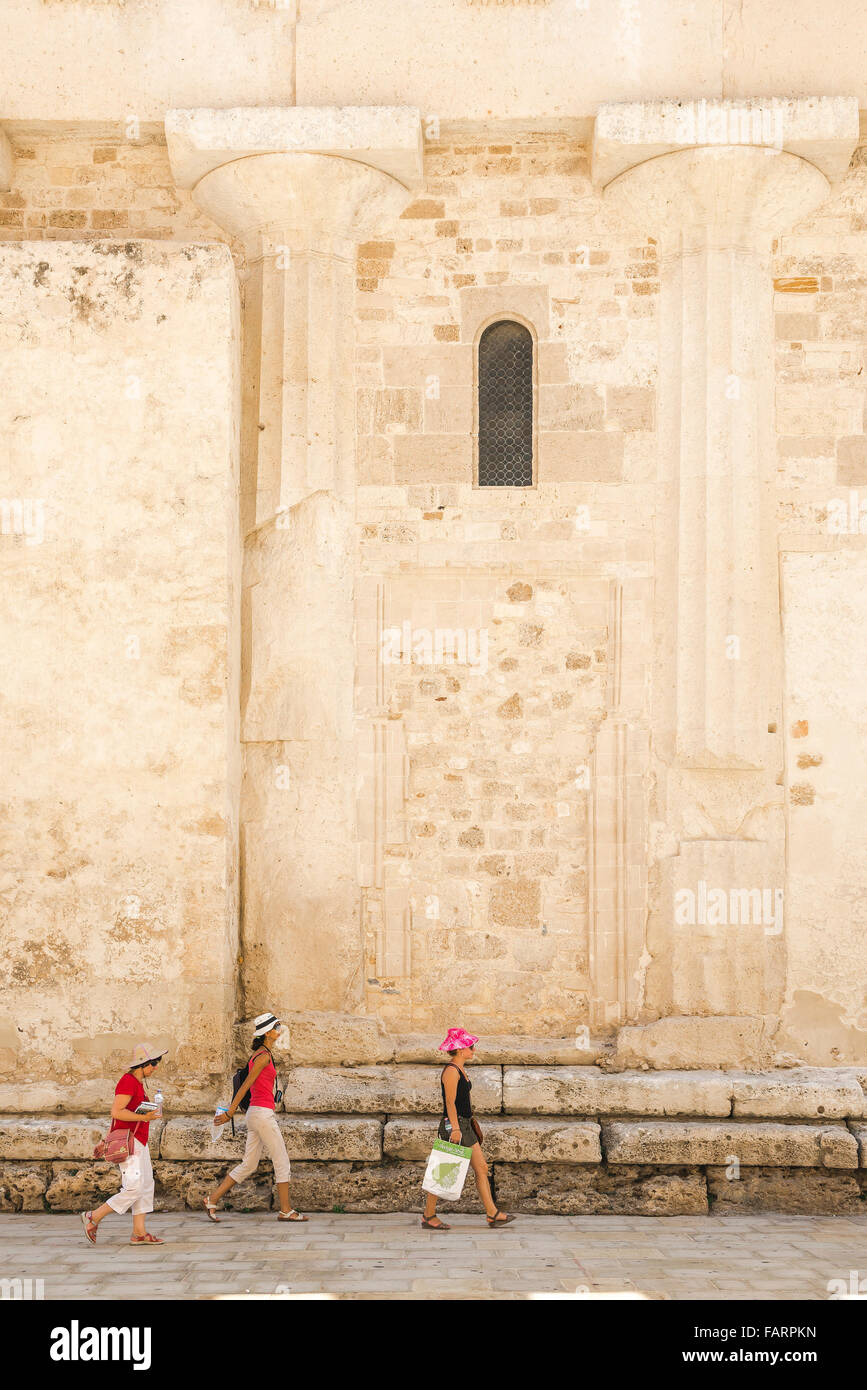 Tourists Sicily, three women tourists walk by a pair of ancient Greek columns embedded in the Duomo (cathedral) wall in Ortigia, Syracuse, Sicily. Stock Photo