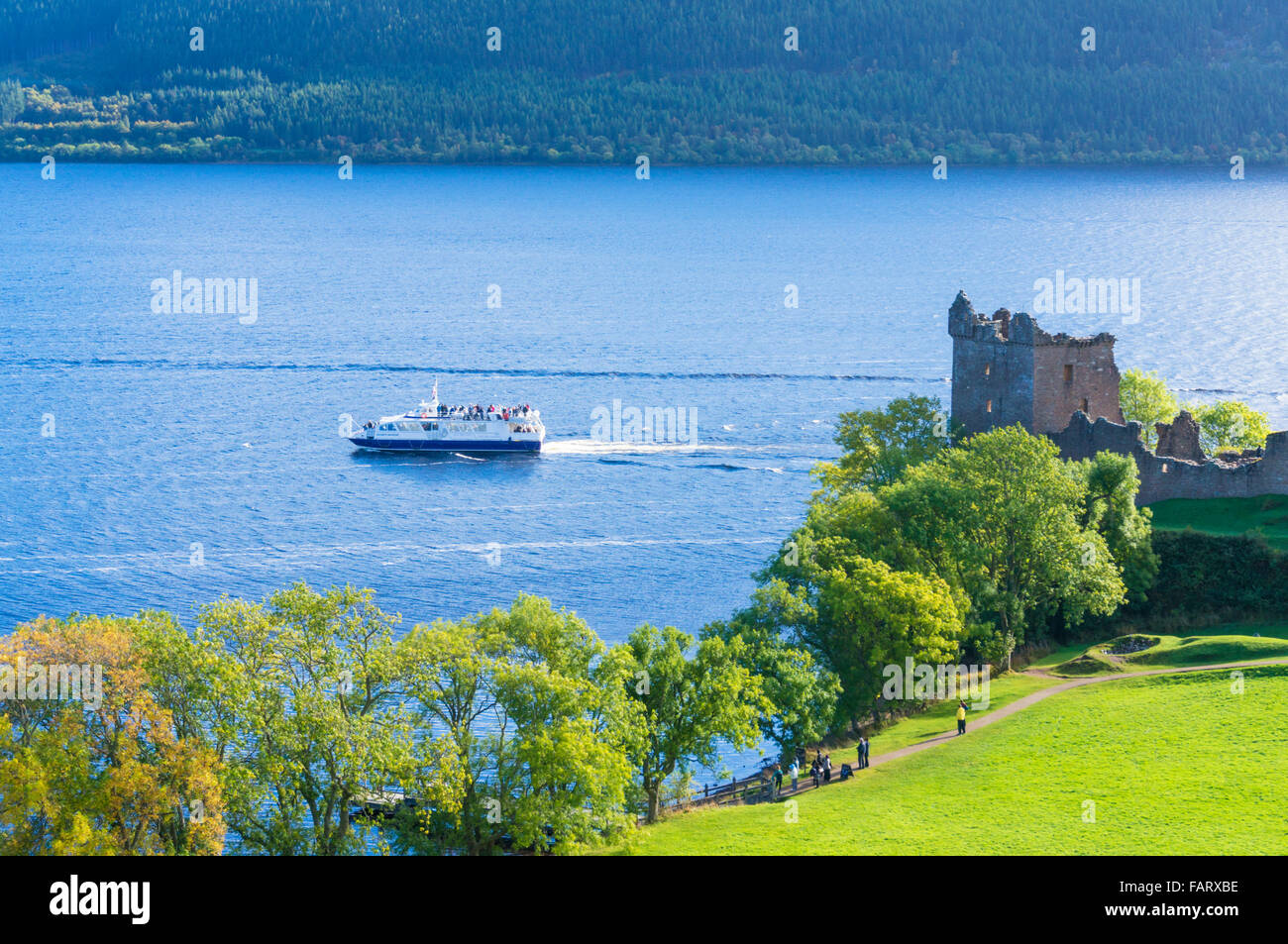 Loch Ness Cruise boat passing close to Urquhart Castle next to Loch Ness on Strone Point Highlands of Scotland UK GB EU Europe Stock Photo