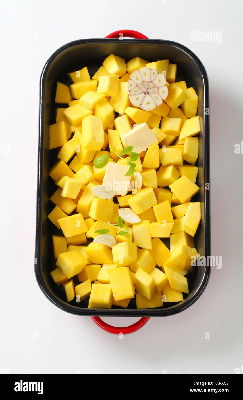 fresh pumpkin cubes with garlic and butter in a baking pan Stock Photo