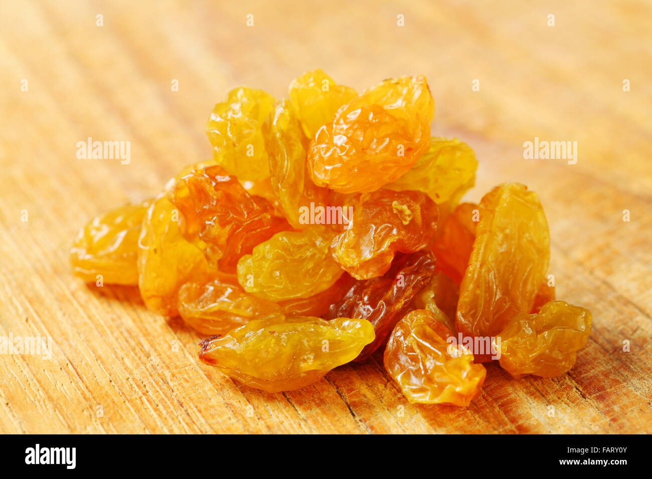 heap of golden-coloured raisins (sultanas) on a wooden background Stock Photo