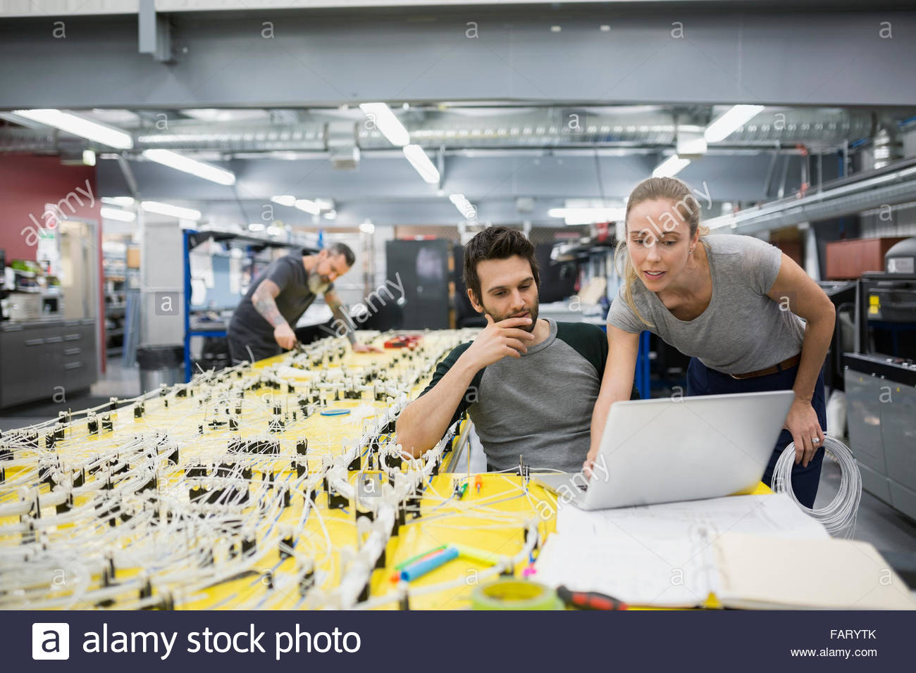Helicopter technicians using laptop at wiring harness - Stock Image