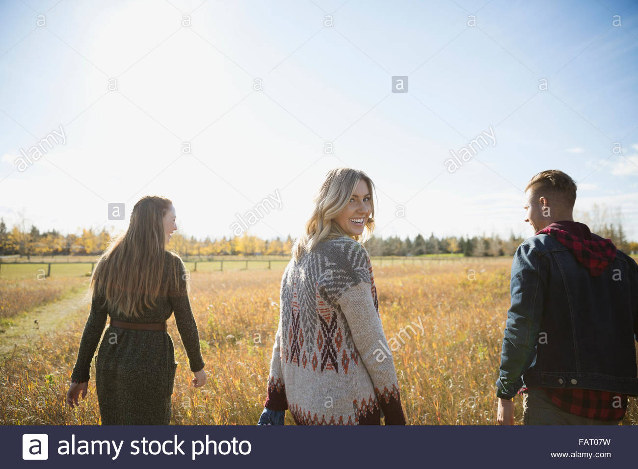 Portrait smiling woman with friends looking back in sunny field Stock Photo
