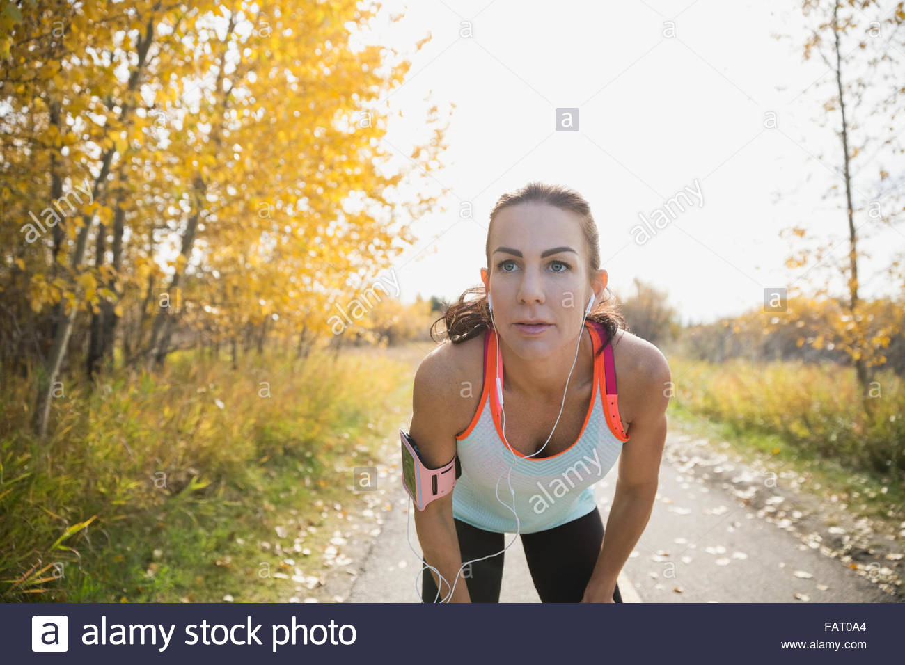 Jogger resting with hands on knees on autumn path Stock Photo