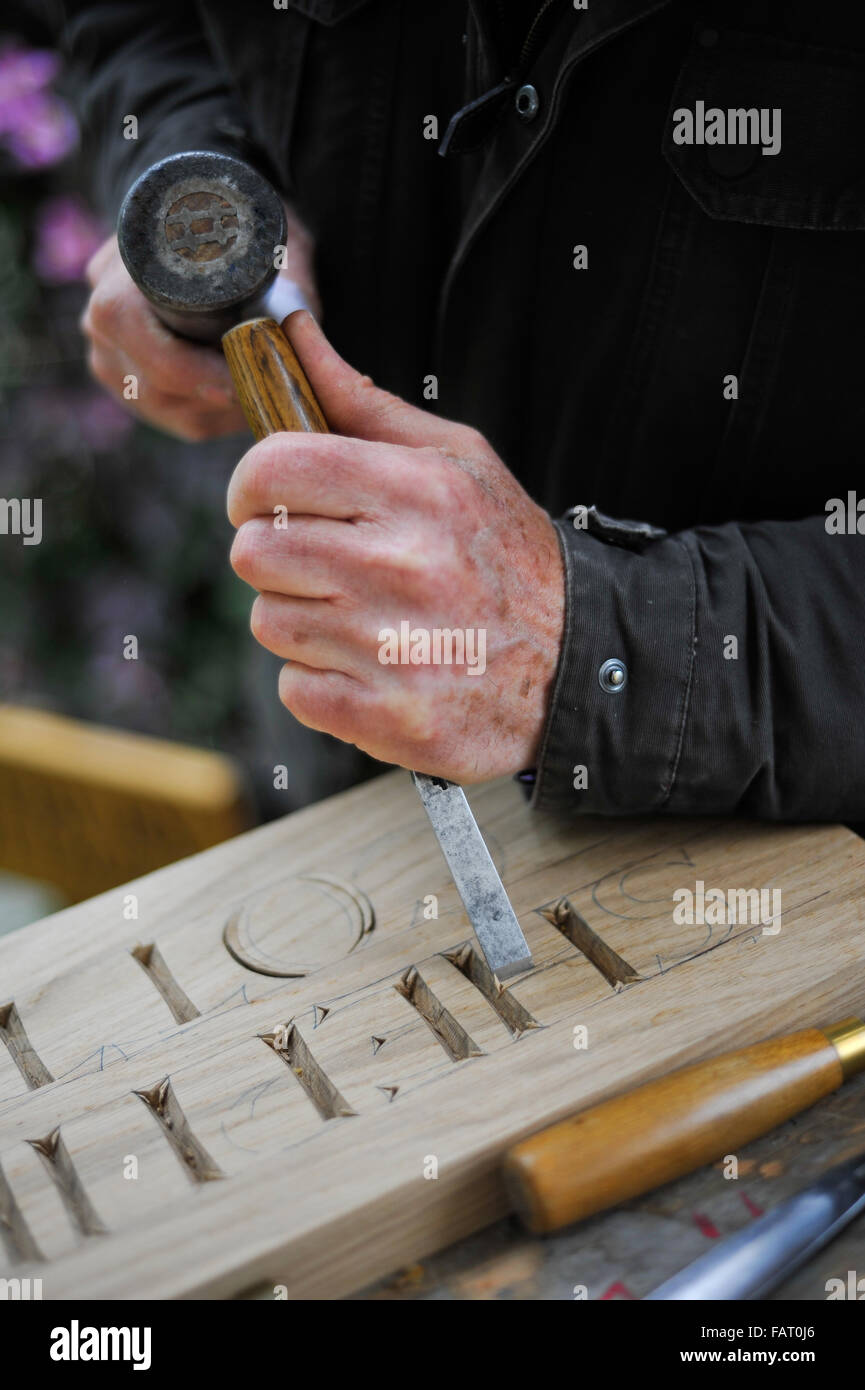 Close up of letter being carved into a piece of wood with a chisel and