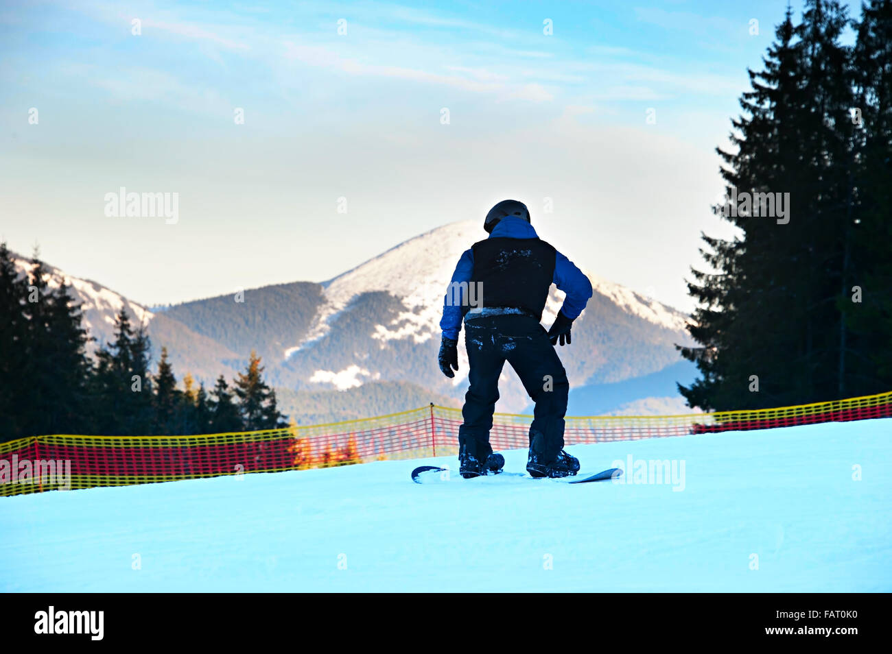 Unrecognizable snowboarder on a mountains slope at sunset in action Stock Photo