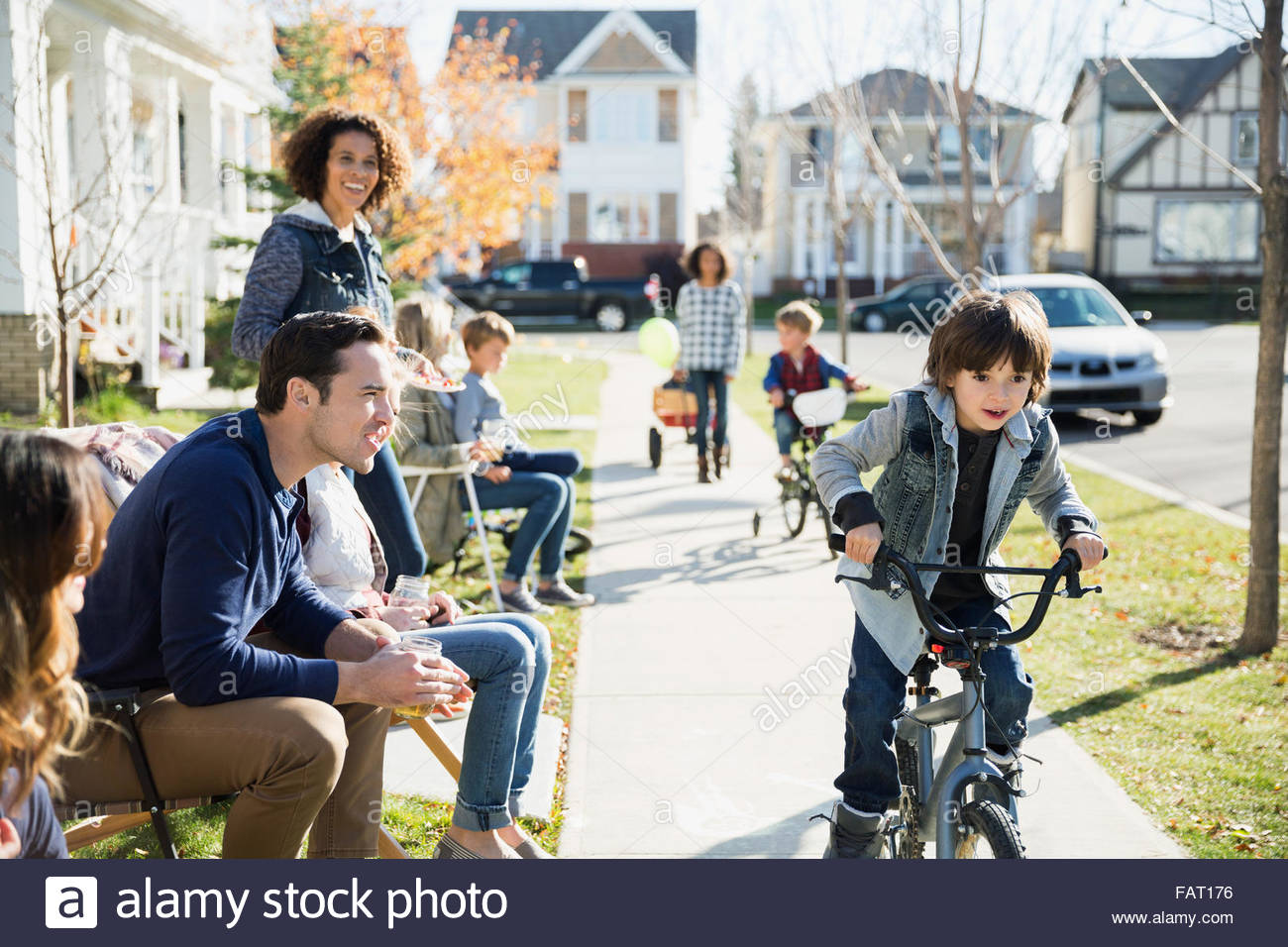 Neighbors watching boy ride bike on sidewalk Stock Photo Alamy