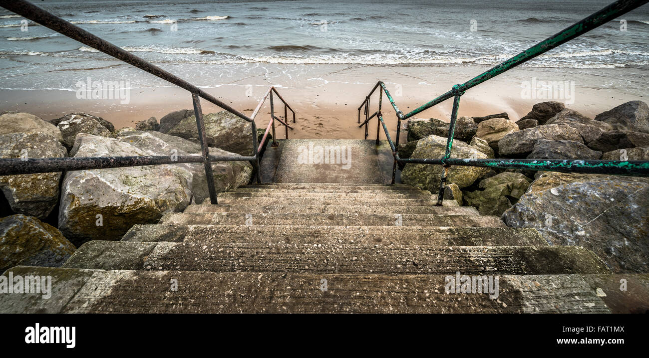 Old concrete steps and iron railings leading to a beach. Stock Photo