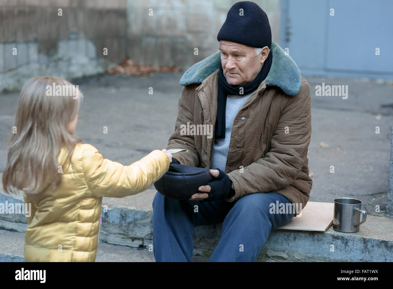 Little girl gives money to the beggar. Stock Photo
