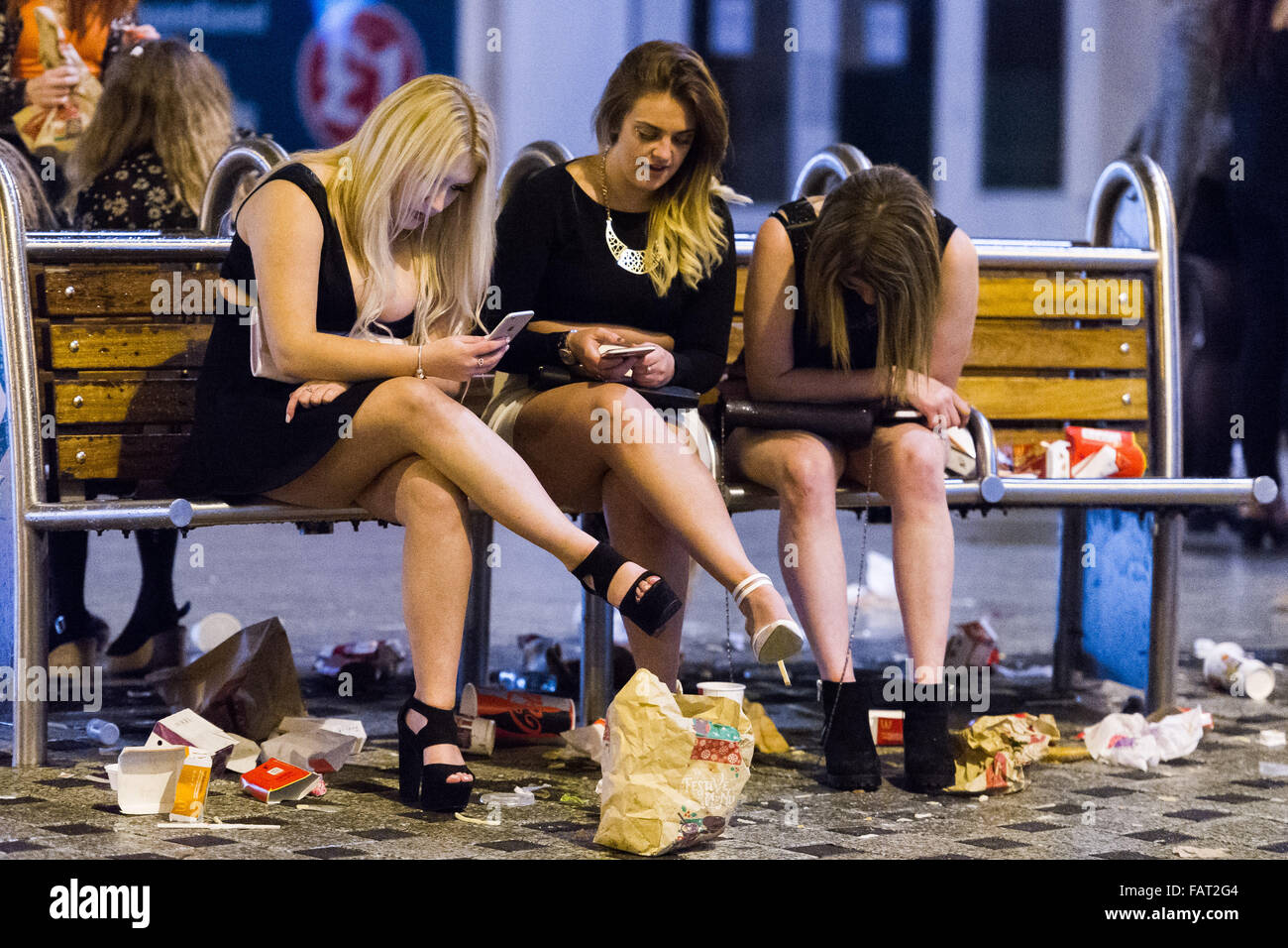 Pictured: A group of women sit on a bench, surrounded by discarded fast food packaging. Re: New Year's Eve in Cardiff, South Wal Stock Photo