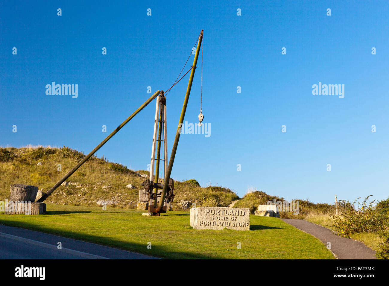 A restored hand crane for lifting stone blocks marks the approach to Portland at Priory Corner, Dorset, England, UK Stock Photo