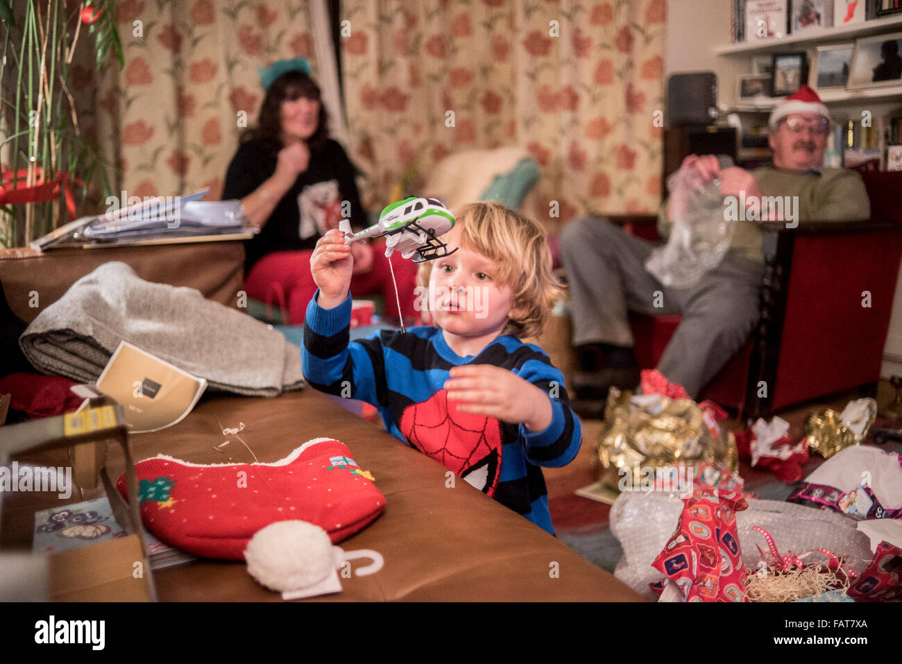 young boy xmas morning opening present of toy helicopter grandparents in the back ground Stock Photo