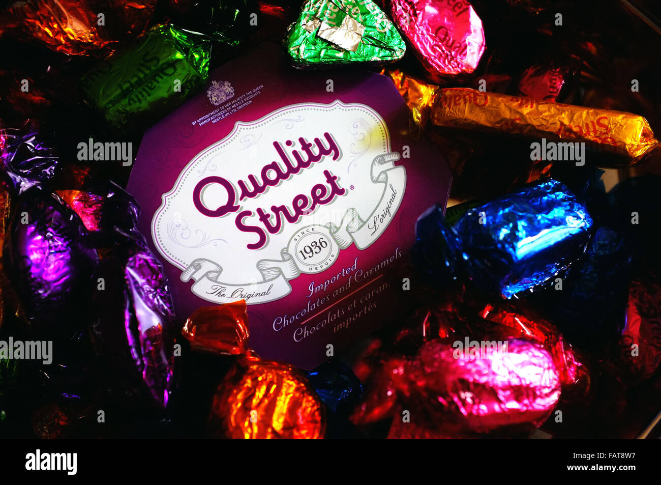 A Quality Street tin surrounded by chocolates in colourful wrappers. Stock Photo