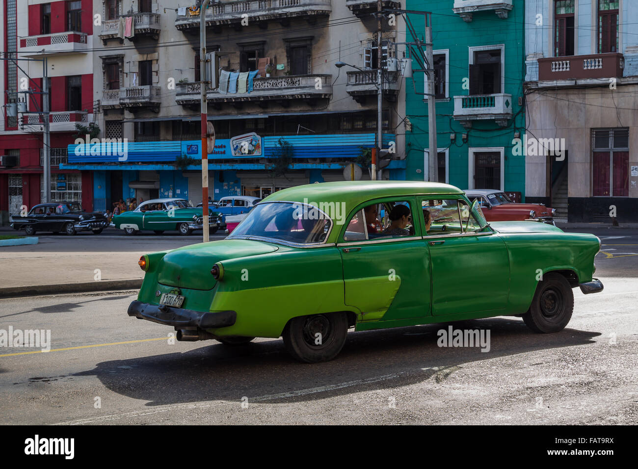 A vintage car in two shades of green prepares to pull out onto Calle San Lazaro as half a dozen other old timers wait. Stock Photo