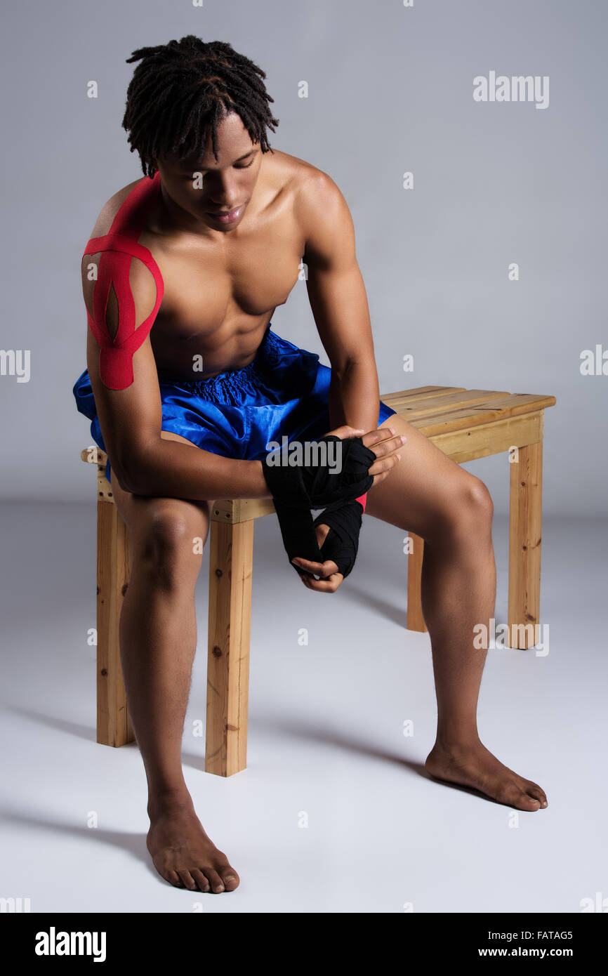 Young muscular athletic male boxer wearing blue boxing shorts and red boxing gloves. Stock Photo