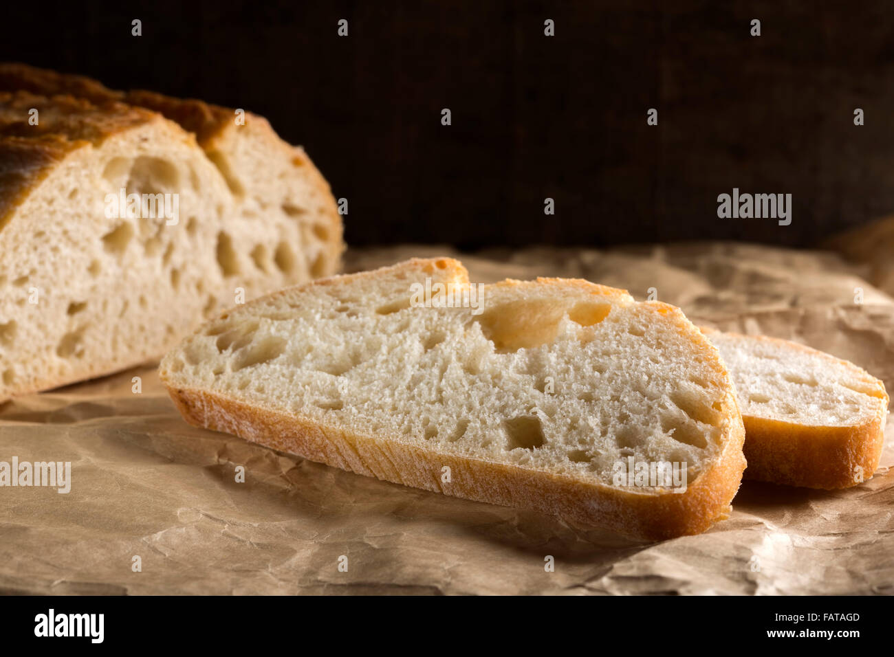 Sliced fresh white bread with browned crust over paper Stock Photo