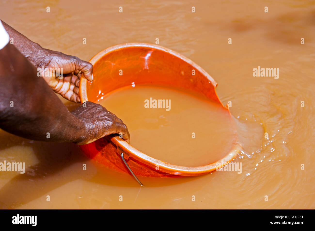 Woman getting water out of a muddy river for use as drinking water