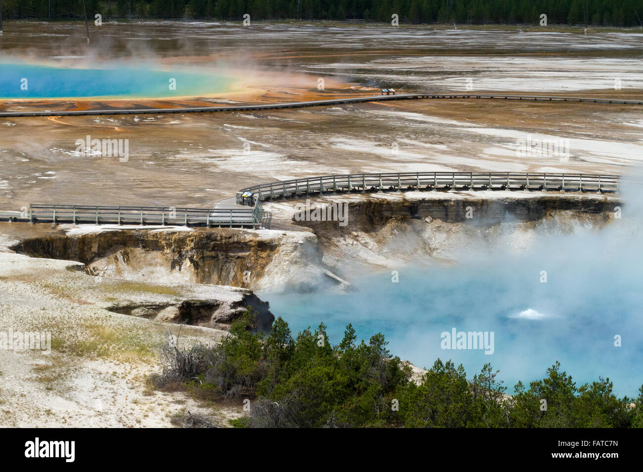 An empty boardwalk lines Excelsior Geyser Crater and Grand Prismatic Spring at the Midway Geyser Basin in Yellowstone Stock Photo