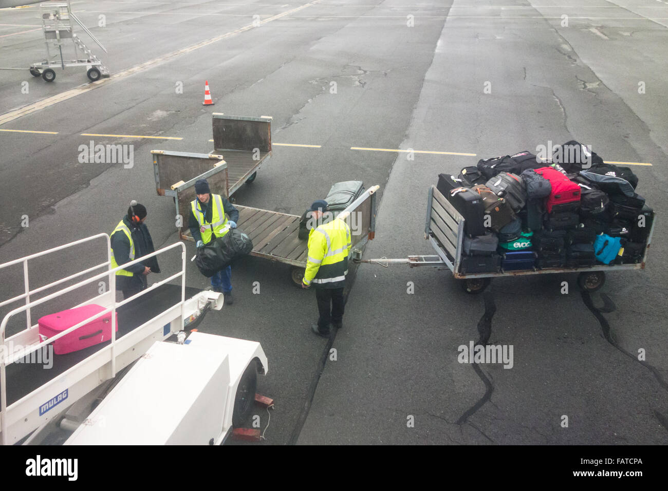 baggage handlers loading suitcases and bags onto plane Stock Photo