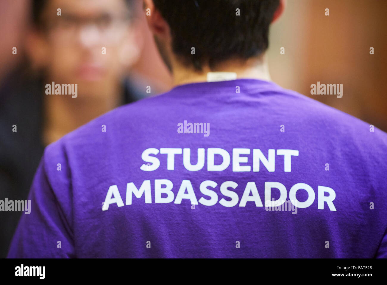 University of Manchester student ambassador with logo on his sweat shirt   purple named helper role model prefect adult educatio Stock Photo