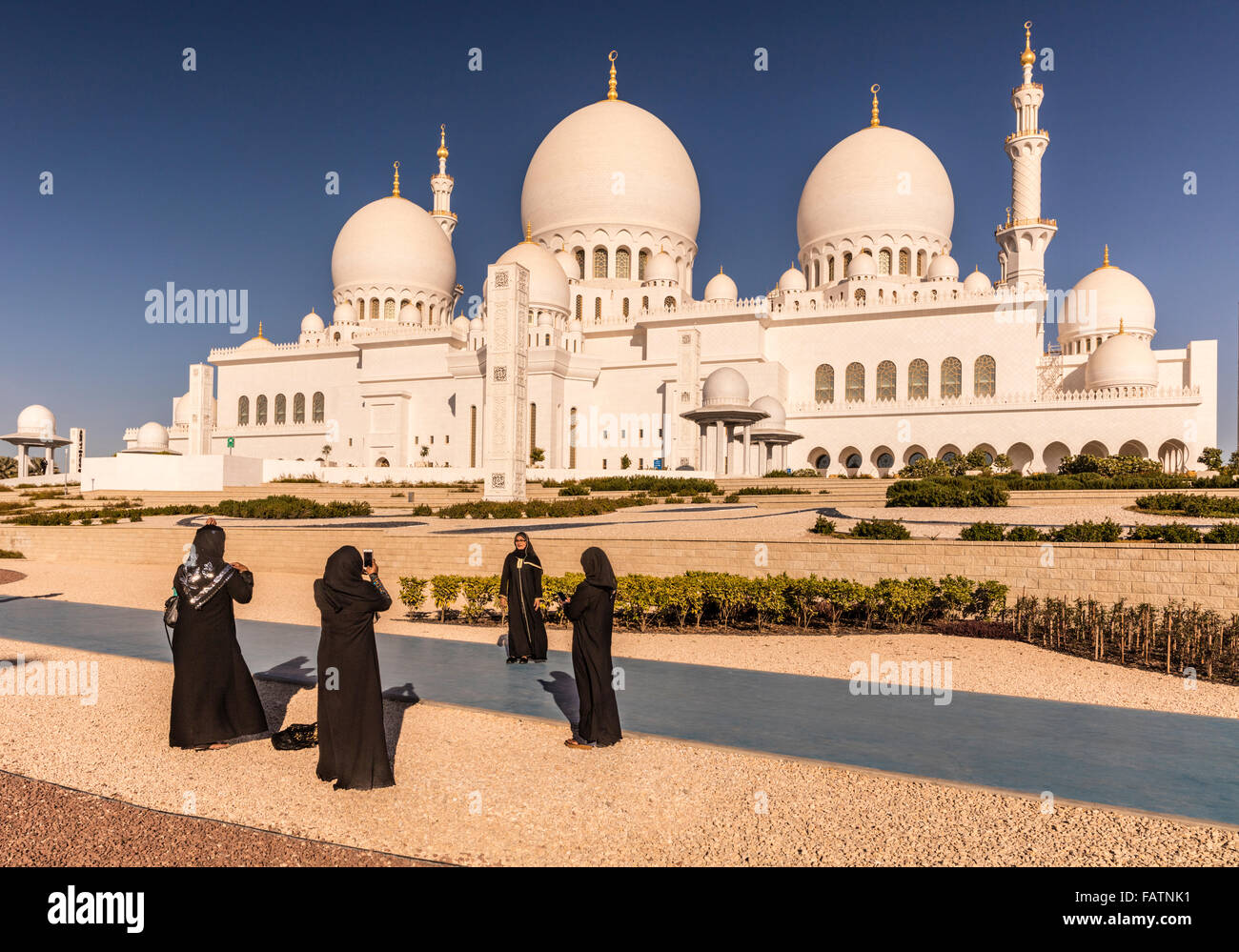 Abaya clad women take photos in front of Sheikh Zayed Grand Mosque, Abu Dhabi, United Arab Emirates Stock Photo