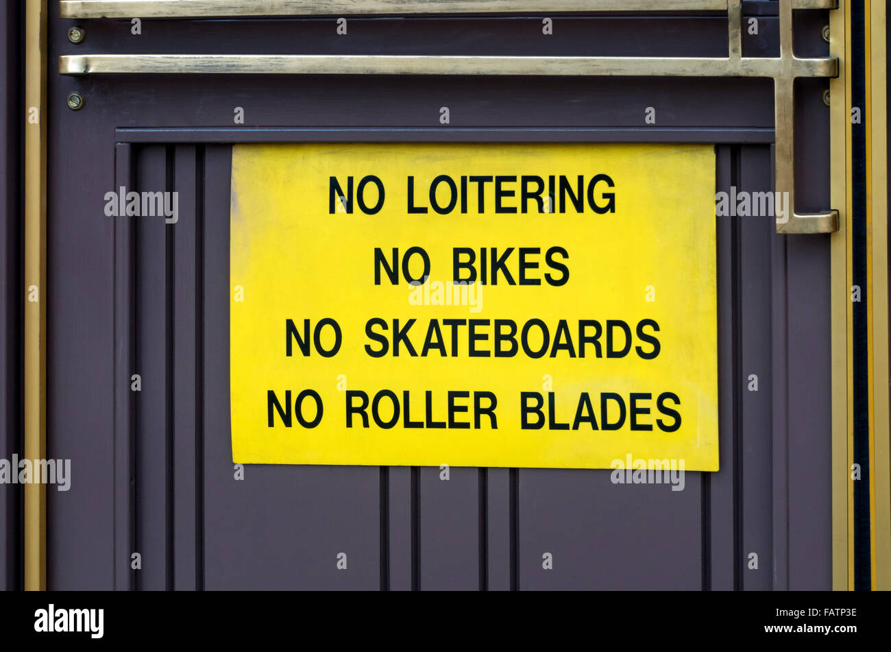 Negative messages on a yellow sign saying: no loitering, no bikes, no skateboards, no roller blades Stock Photo