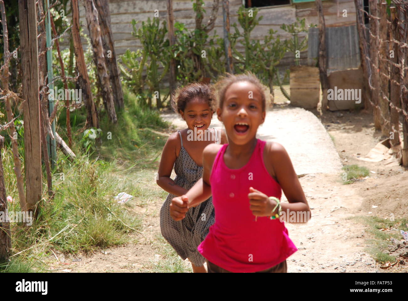 Two girls running down the path in a neighborhood of Luperon,Dominican Republic. Stock Photo