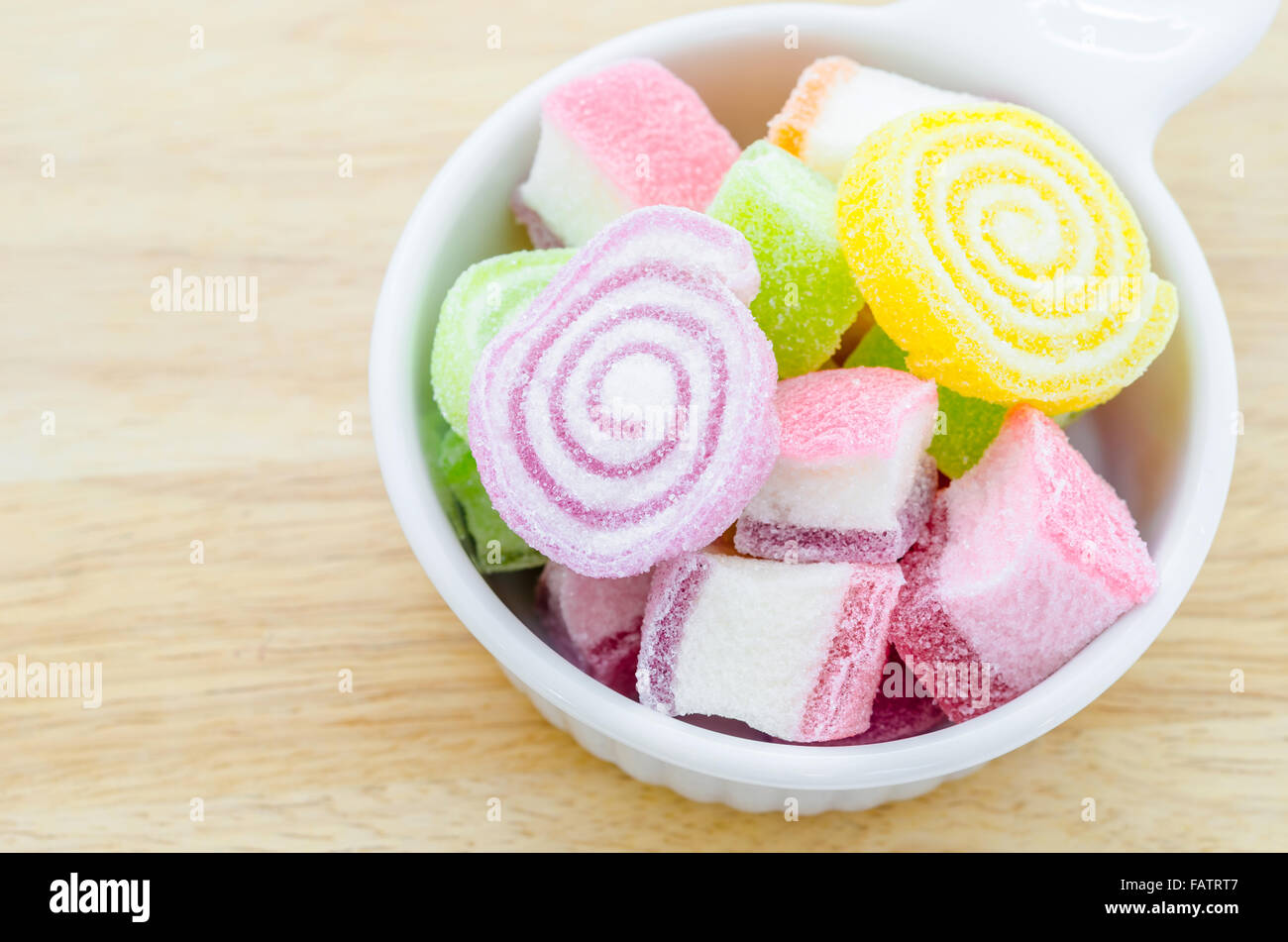 Colorful sweet jellies with sugar in cup on wooden background. Stock Photo