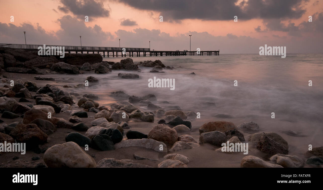 Seascape with jetty during a dramatic cloudy sunset at Paphos area in Cyprus Stock Photo
