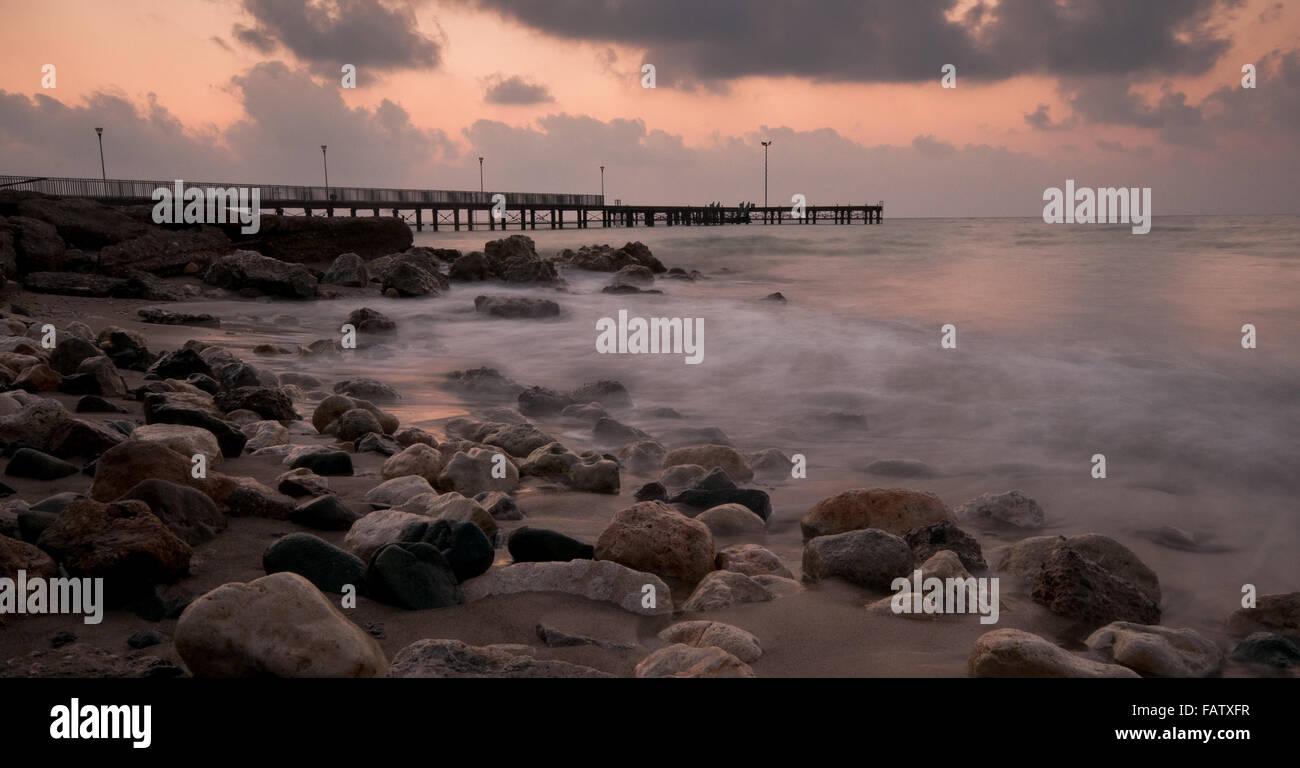 Seascape with jetty during a dramatic cloudy sunset  at Paphos area in Cyprus Stock Photo