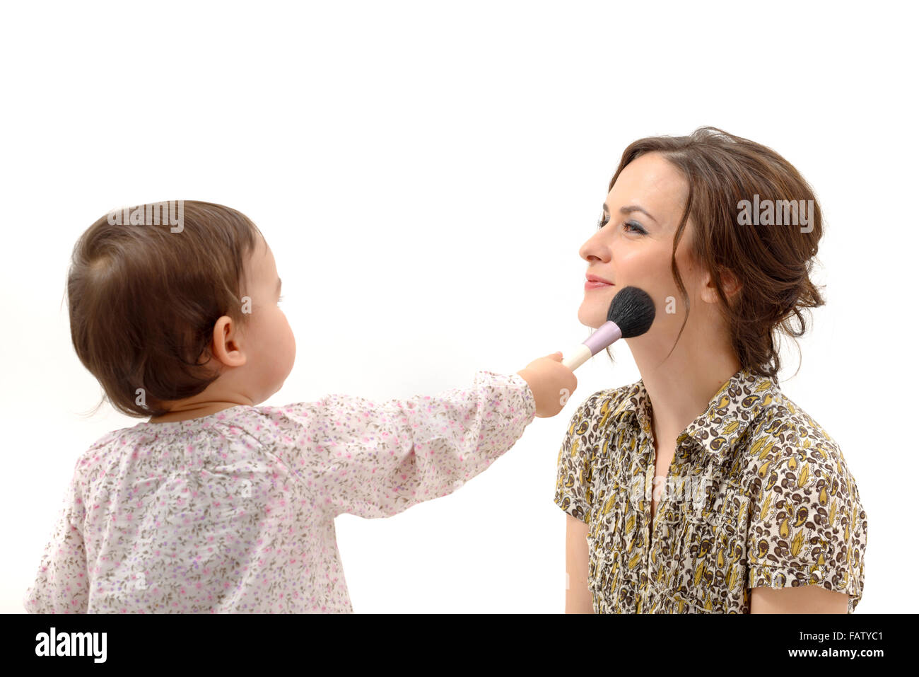 little girl putting on the makeup to her mother Stock Photo