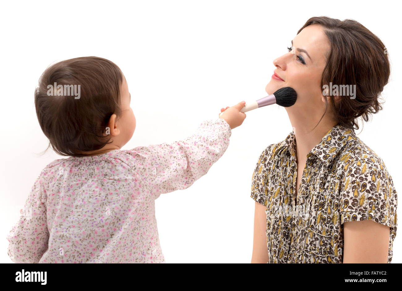 little girl putting on the makeup to her mother Stock Photo